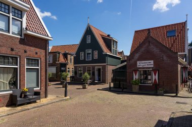 VOLENDAM, NETHERLANDS - Temmuz 07, 2023: Güneşli bir günde tipik evleri ile güzel bir balıkçı köyü Volendam. Hollanda.