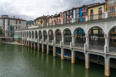 TOLOSA, SPAIN - JULY 19, 2023:Arcades of the Tinglado market and multicolored buildings in the old town of the city of Tolosa since Oria river, Basque Country, Spain. clipart