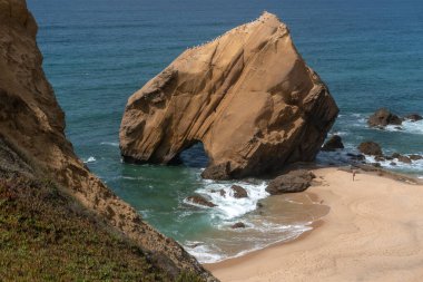 Santa Cruz plajı ünlü doğal kemer düzeniyle gün batımında, Portekiz.