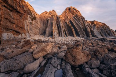 İspanya 'nın kuzeyinde Cantabria' da gün batımında Portio plajında renkli kaya oluşumları (Flysch).