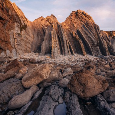 İspanya 'nın kuzeyinde Cantabria' da gün batımında Portio plajında renkli kaya oluşumları (Flysch).