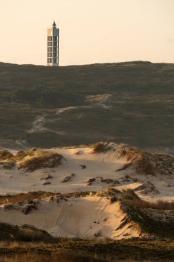 Frouxeira lighthouse since Valdovino beach with its sand dunes in the coast of Galicia at sunset in a sunny day. A Coruna, Spain. clipart