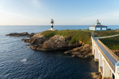 RIBADEO, SPAIN - MAY 08, 2022: Pancha island lighthouse at sunset in Ribadeo coast and the bridge to cross, Lugo province, Galicia, Spain clipart