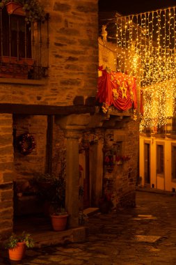 PUEBLA de SANABRIA, SPAIN - 26 Aralık 2022: Ortaçağ Puebla de Sanabria köyünün güzel caddesi, Zamora 'da, gece yılbaşı aydınlatmasıyla. İspanya