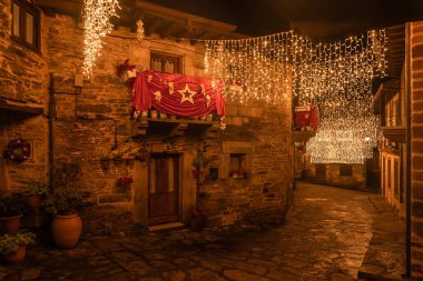PUEBLA de SANABRIA, SPAIN - 26 Aralık 2022: Ortaçağ Puebla de Sanabria köyünün güzel caddesi, Zamora 'da, gece yılbaşı aydınlatmasıyla. İspanya