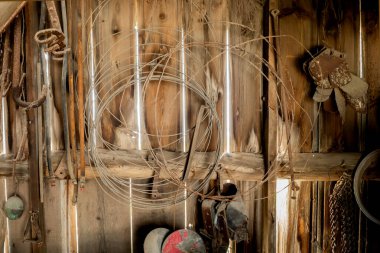 Eski bir barakanın ahşap duvarı ve duvarında eski çiftlik eşyaları asılı.. 