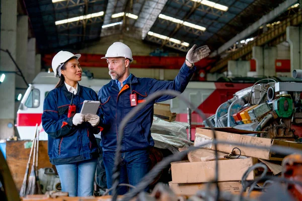 Factory worker man explain about work in workplace to Asian factory technician woman and they work as teamwork for industrial business successful.