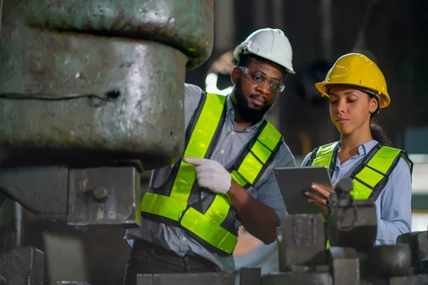 African American factory woman hold tablet and use to explain about machine function for her coworker and they also maintenance or repair process.