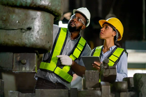 African American factory woman hold tablet and discuss about machine function with her coworker and they also maintenance or repair process.