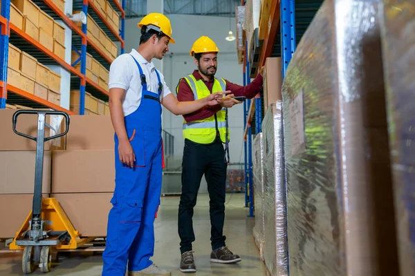 stock image Asian professional technician ask for the detail of product with his warehouse coworker during work with using scanner to check details of the product in workplace area.