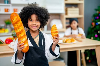 Afro-Amerikalı kız mutfakta yemek pişirme dersinde arkadaşının önünde duruyor ve bu çalışmadan memnun görünüyorlar..