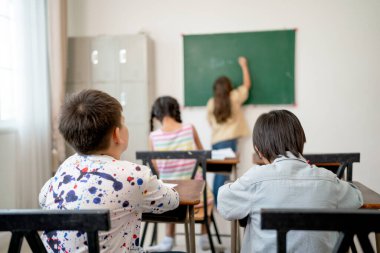 Oğlanların arkası, arkadaşları sırasında sınıfın arkasında oturur. Bir kız, okuldaki çocuklar için mutluluk konsepti üzerine bir şeyler yazar..