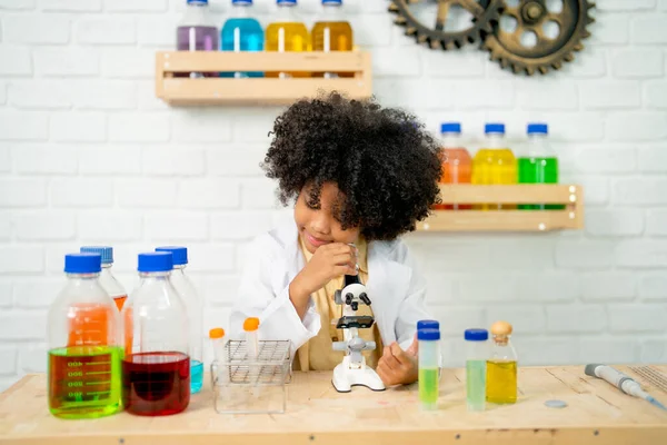 非洲裔美国女孩用显微镜在实验室或课堂上进行分析和练习 她看上去很开心 也很享受这门课 — 图库照片