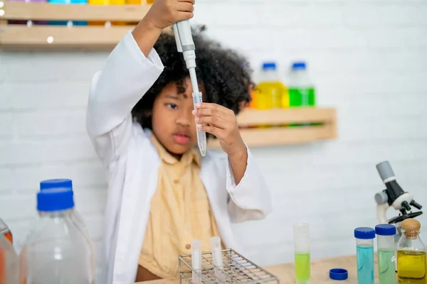 非洲裔美国女孩通过在科学课上使用自动吸盘和像实验室里的年轻科学家那样使用各种颜色化学物质来做实验 — 图库照片