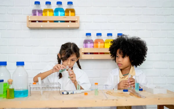 两个小女孩用不同的实验设备在科学课上练习 全神贯注地工作 — 图库照片
