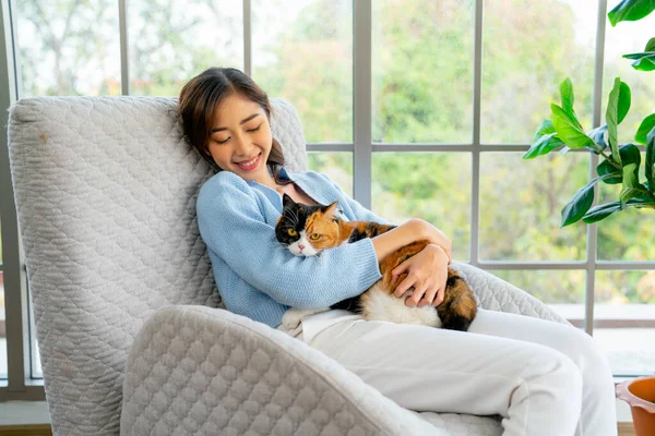 stock image Asian woman hold and hug cat also lie on sofa in living room with day light and she look happiness with smiling.