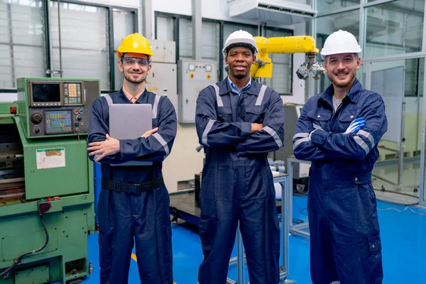 stock image One African American and two Caucasian technician or engineer workers stand with arm crossed and look at camera also stay in front of factory machine in workplace.