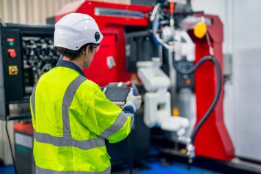 Profesyonel teknisyen veya mühendis, iş yerinde fabrika robotik kol makinesi ile çalışmak için denetleyici kullanır.