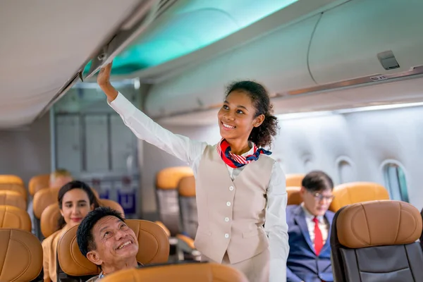 Close up view air hostess or airline staff walk to close luggage compartment of airplane before take off and bring the passenger to the destination with happiness.