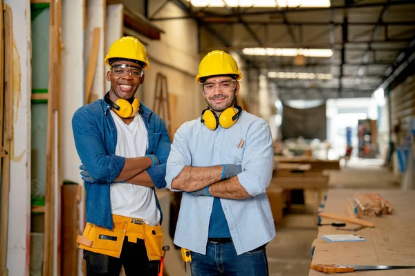 Portrait of African American and Caucasian carpenter man stand with arm crossed and smiling also look at camera in wood factory workplace.