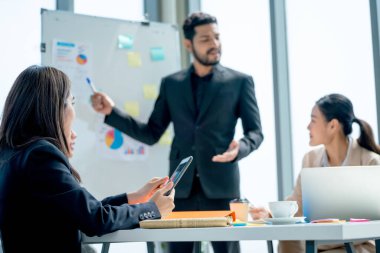 Kapatın Asyalı iş adamları projeyi beyaz tahtada gün ışığında iş arkadaşlarına sunuyorlar ve birlikte çalışmaktan mutlu görünüyorlar..