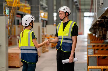 Mühendis ya da fabrika teknisyeni erkek ve kadın işçiler, demiryolu üzerindeki elektrikli trenin yanındaki işyerlerinde birleşik projenin başarısı için el sıkışıyor..