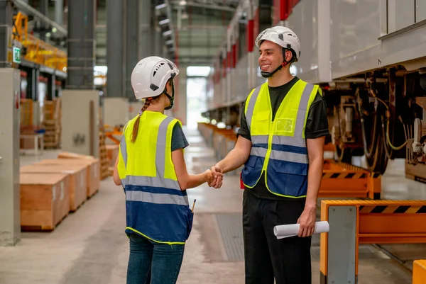 Engineer or factory technician worker man and woman shake hands for the success of joined project together in workplace near the electric train on rail.