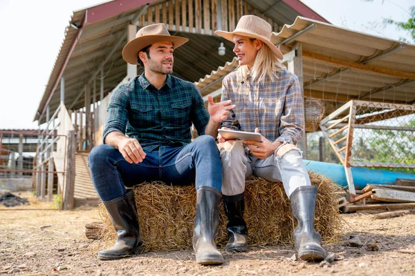 stock image Caucasian man and woman farmers sit on straw and discuss about working with man explain the process and they look happy and relax after work in farm together with day light.