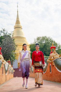Geleneksel elbiseli Taylandlı kadınların dikey görüntüsü birlikte yürüyüp Tayland 'ın kuzeyindeki ünlü tapınağın geçidinde tartışıyorlar..