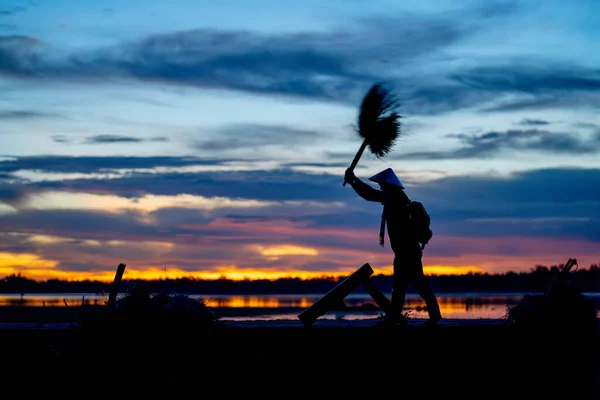 Silhouette of man work with local tools to get rice grain and use traditional method for working during early morning in concept of Asian famer lifestyle and happiness life.