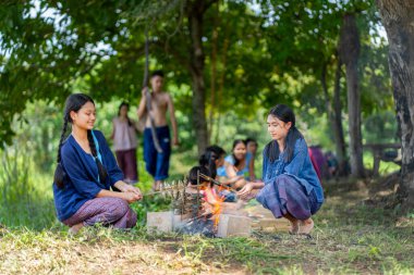 Bir grup Asyalı çiftçi ve genç kız, erkek ve çocuk pirinç tarlasında yemek yemekten hoşlanıyorlar ve birlikte aktivitelere katılmaktan mutlu görünüyorlar..