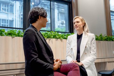 Kafkas iş kadını teneffüste Asyalı iş arkadaşıyla oturup tartışır ya da şirketin çalışma ortamında dinlenir..