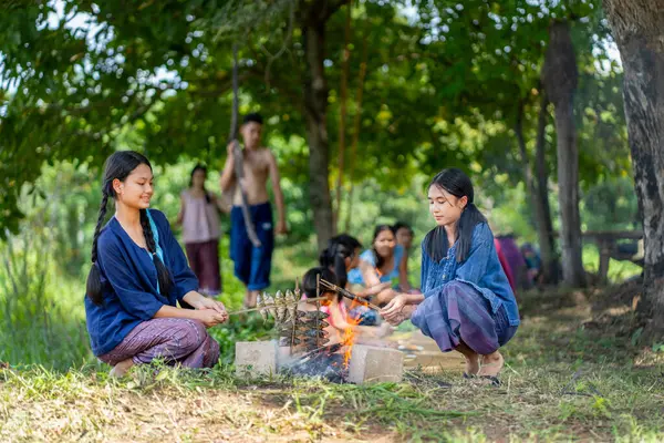 Bir grup Asyalı çiftçi ve genç kız, erkek ve çocuk pirinç tarlasında yemek yemekten hoşlanıyorlar ve birlikte aktivitelere katılmaktan mutlu görünüyorlar..
