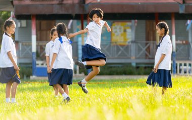 Kapalı giyim Asyalı kızlar öğrenci üniforması giyip okulun çim tarlasında kauçuk ip üzerinde zıplamaktan zevk alırlar..