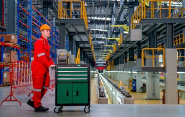 Profesyonel teknisyen, elektrikli ya da gökyüzü tren fabrikası işyerindeki rayların önündeki el arabasını ya da araç gereçleri itiyor..