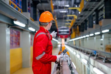 Güvenlik üniformalı profesyonel teknisyen, fabrika işyerindeki elektrik veya gökyüzü trenini işaret ediyor..