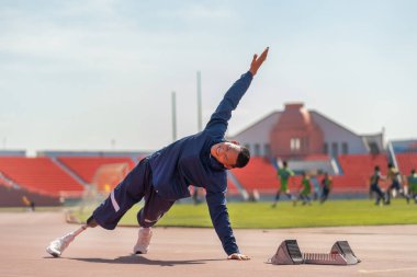 Sporcu sporcu atlet bacak hareketlerinde protezle vücudunu ısıtmak için yan yatar ve bir elini stadyumun sahasına kaldırır. Spor konsepti..