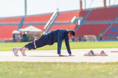 Spor adamı atleti, spor konsepti olan stadyumdaki koşu ekipmanının yanında şınav çekerek vücut ısıtma hareketi üzerine protez takmış..