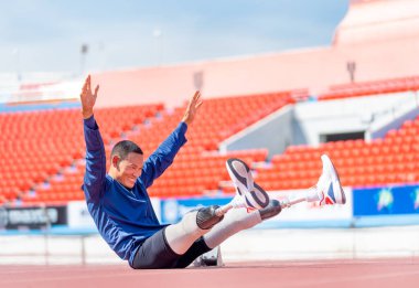 Spor sporcusu, vücudunu ısıtmak için kollarını ve bacaklarını stadyumda dinlendirecek bir protez takıyor. Spor konsepti..