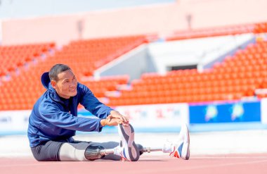 Spor adamı atleti, bacak hareketlerine protez takmış bacağını uzatarak ve stadyumdaki piste geri dönerek vücut ısıtmaya çalışıyor..