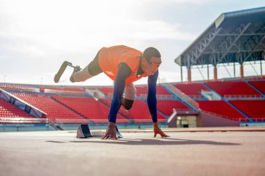 Bacağında protezi olan sporcu bir sporcu uzandı ve bir bacağını arkaya uzattı. Ayrıca stadyumdaki antrenmandan önce ısınmak için sabırsızlanıyordu..