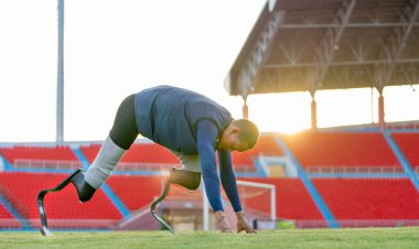 Sporcu atlet protez bacakları gece hafif ışıklarıyla stadyumda koşma pozisyonunda kalıyor..