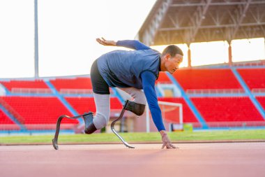Sporcu sporcu protez bacakları pistte koşmaya başlama pozisyonunda kalsın ve akşamın yumuşak ışıklarıyla stadyuma baksın..