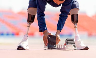 Bacağında protezi olan sporcu bir atlet stadyumdaki koşu ekipmanlarını hazırlıyor. Spor konsepti.