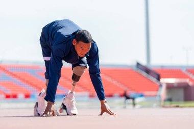 Stadyumdaki pistte koşmaya başlama hareketinde protezi olan sporcu bir sporcunun önden görünüşü. Spor konsepti.