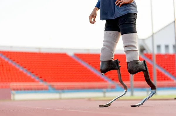 Close up athlete prosthesis legs of sport man stand and warm up legs on track in the stadium.