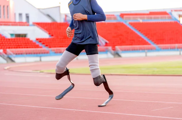 Close up sport man athlete prosthesis legs stand and warm up legs before run training on track in the stadium.