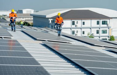 Caucasian technician workers walk together to check and maintenance the solar cell panels on rooftop of the building or factory. clipart