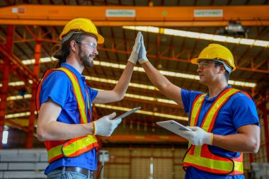 İki beyaz teknisyen el ele tutuşuyor ve fabrika işyerinde mutlu görünüyorlar. Endüstriyel fabrika konseptinde iyi yönetim.