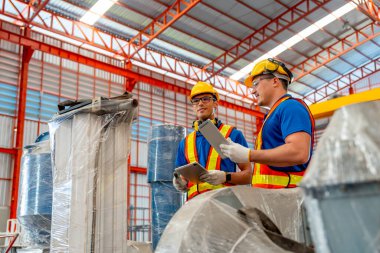 İki fabrika işçisi fabrika işyerindeki makineyi tartışıp kontrol ediyorlar..
